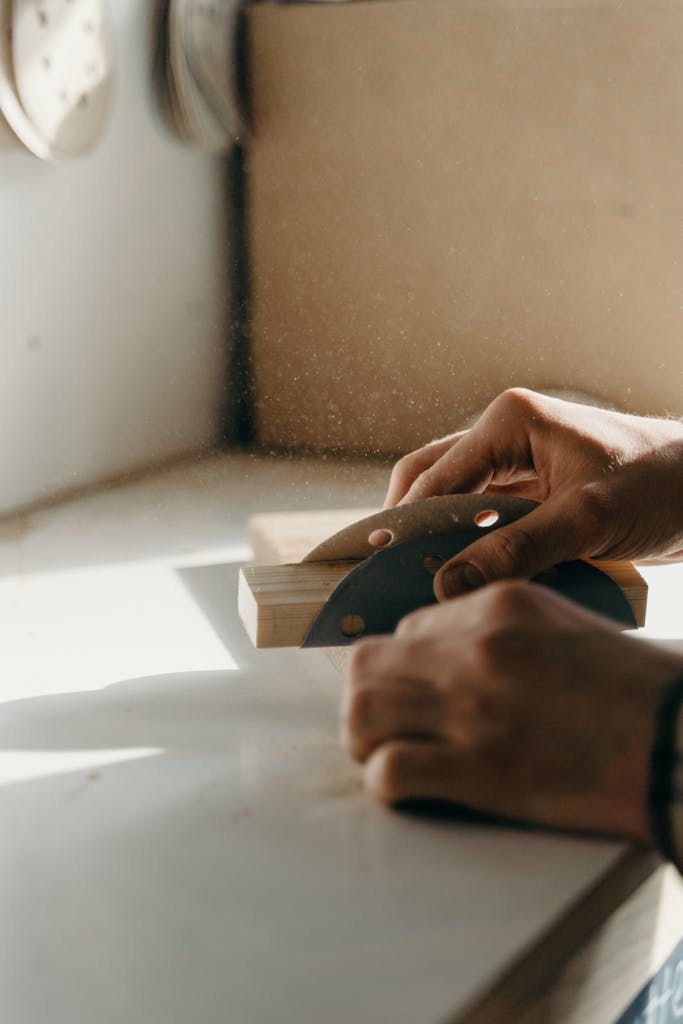 A close-up shot of hands skillfully sanding wood indoors, capturing the essence of craftsmanship.