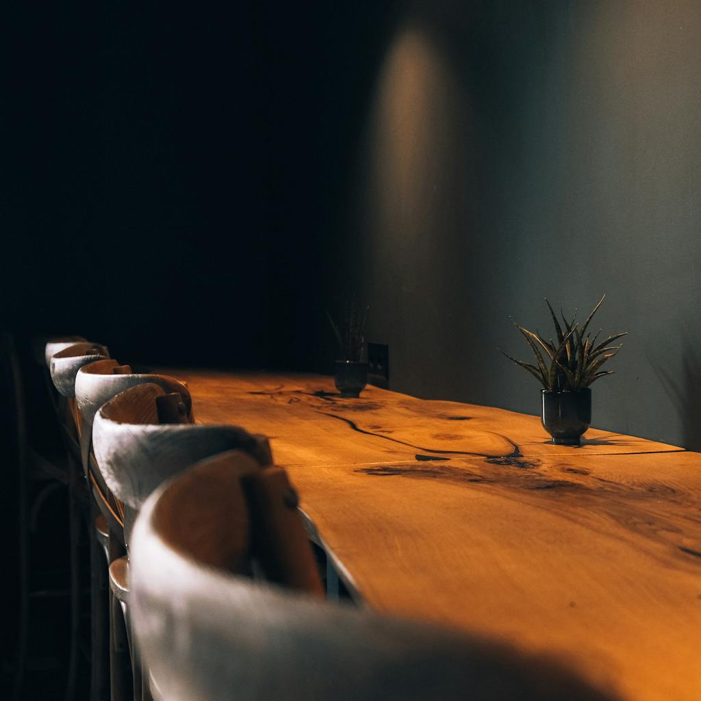A modern wooden table with potted plants, captured in a cozy, dimly lit room.