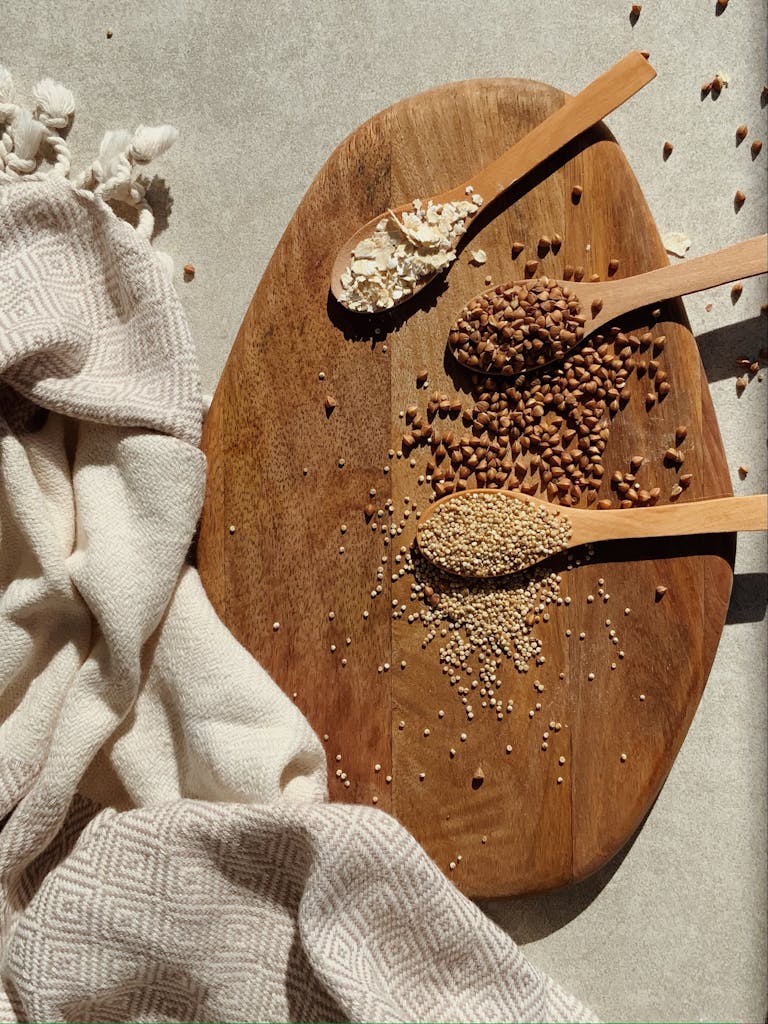 Artistic flatlay of grains on wooden board with textured fabric in warm lighting.
