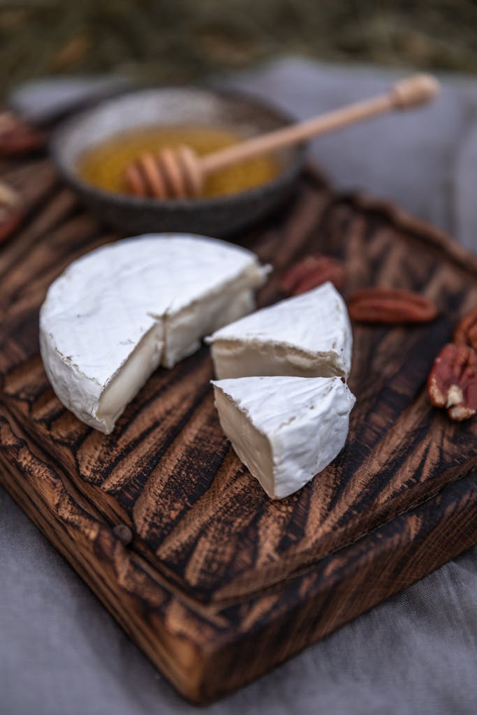 Close-up of brie cheese on a wooden board with honey and nuts.