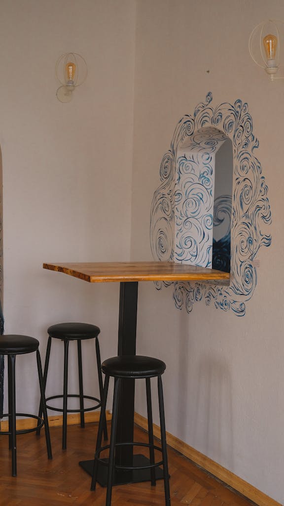 Cozy café corner featuring a high wooden table and artistic wall designs, perfect for urban interiors.
