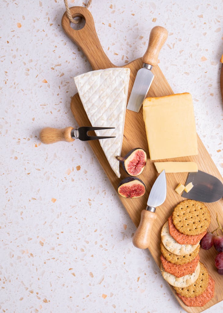 Delicious charcuterie board featuring cheeses, crackers, and figs on a wooden board.