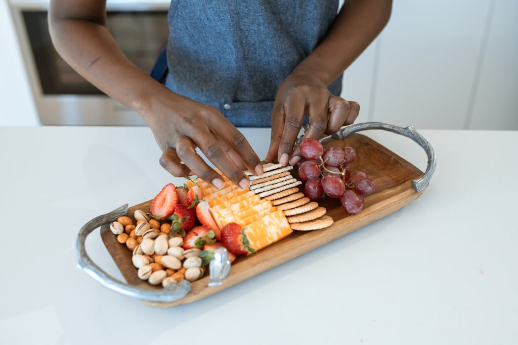 Delicious charcuterie board with cheese, grapes, nuts, and strawberries arranged artfully on a wooden platter.