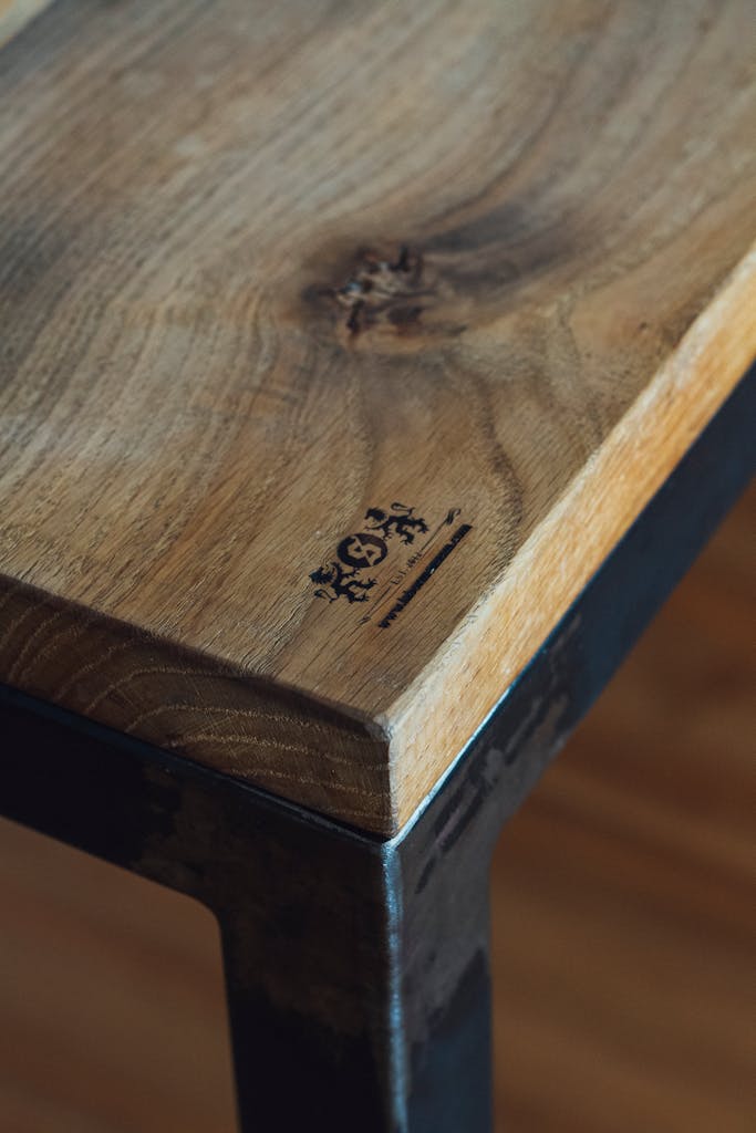 Detailed view of a wooden table's corner showcasing texture and emblem design.