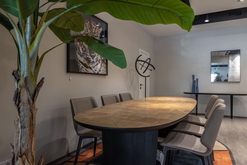 Elegant conference room with a wooden table, chairs, and tropical decor, ideal for meetings.