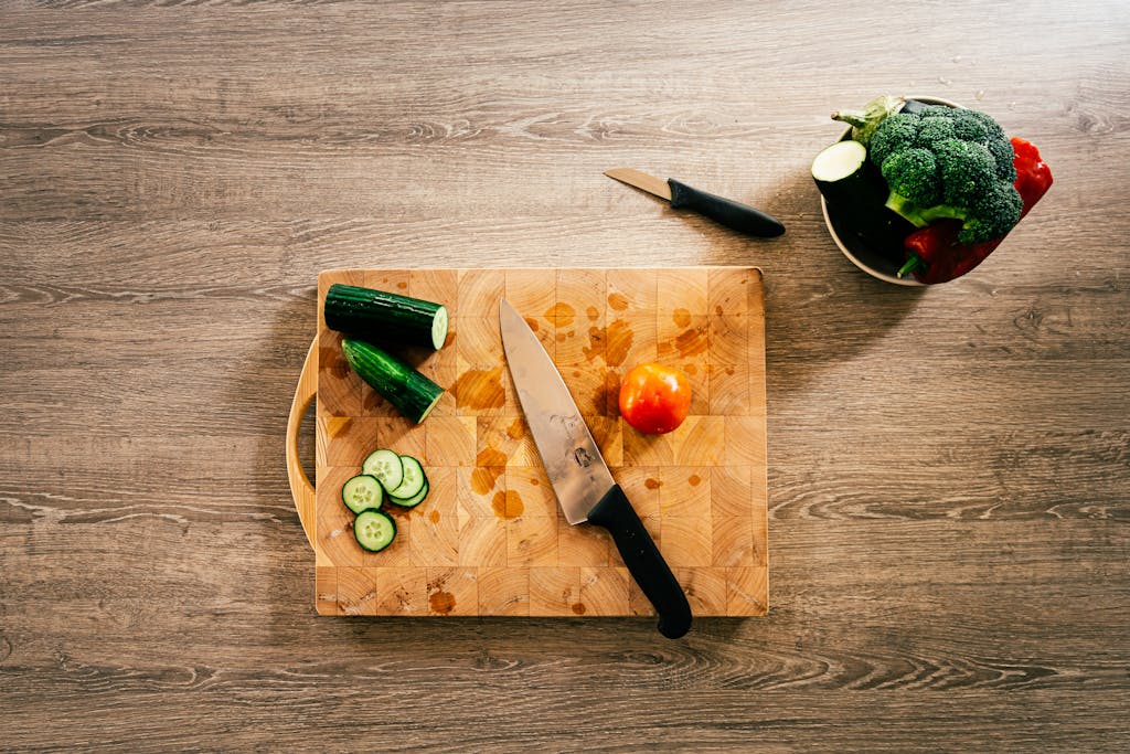 Organic vegetables and knife on wooden chopping board, ideal for healthy cooking themes.