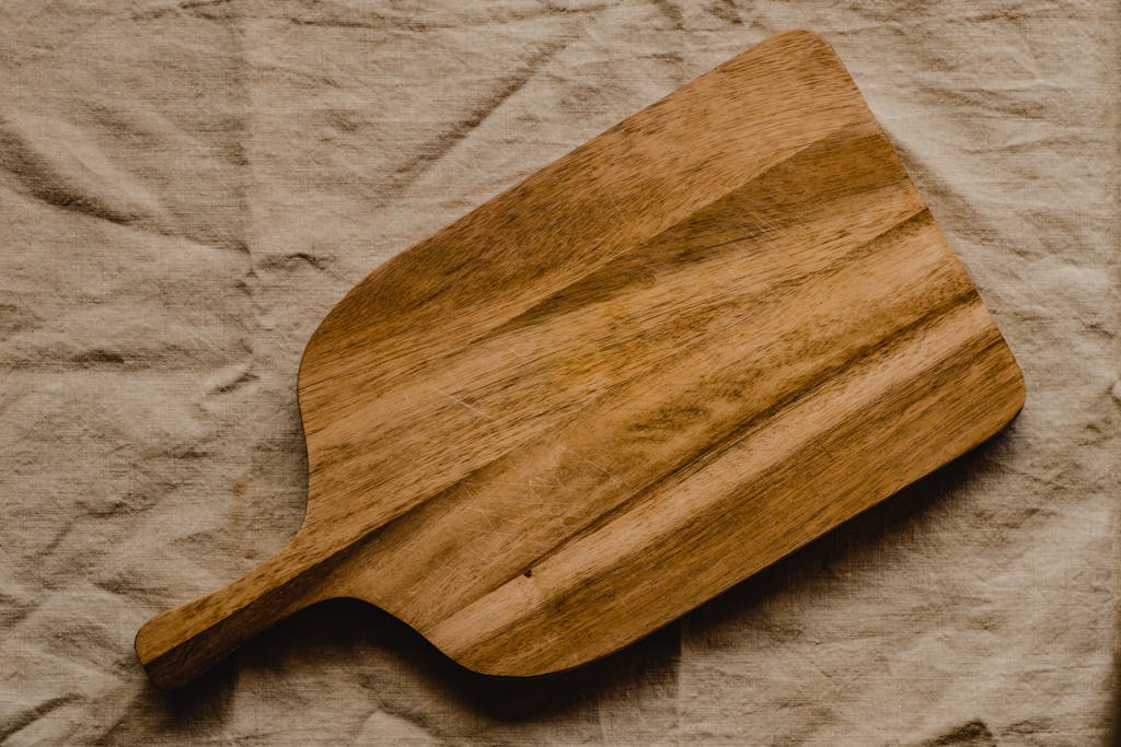 Rustic wooden chopping board on textured linen surface for kitchen decor