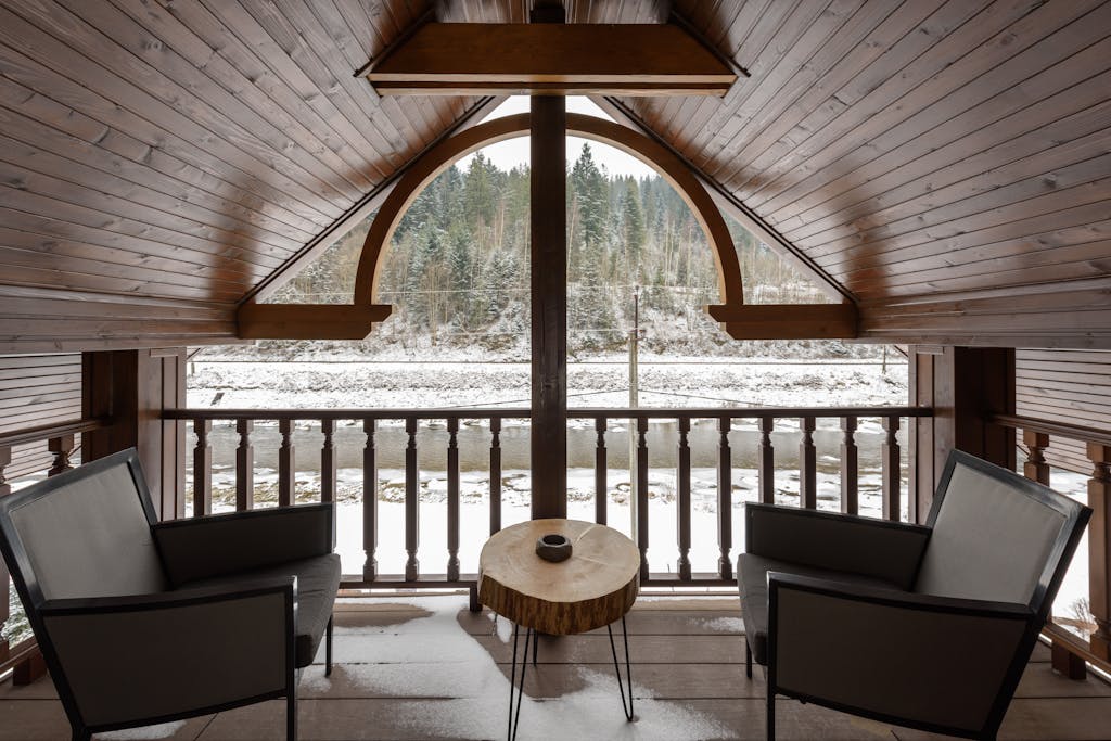 Warm attic space with armchairs and scenic snowy view, perfect for winter relaxation.